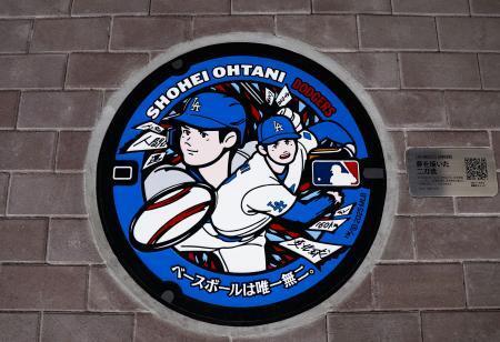 　米大リーグ・ドジャースの大谷翔平選手が投打の二刀流で活躍するイラストを描いたマンホールのふた＝１６日午後、岩手県奥州市のＪＲ水沢江刺駅前