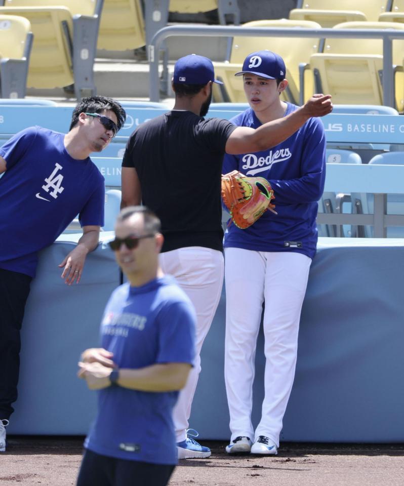 　試合前練習でチームメートと話をする佐々木（右）＝共同