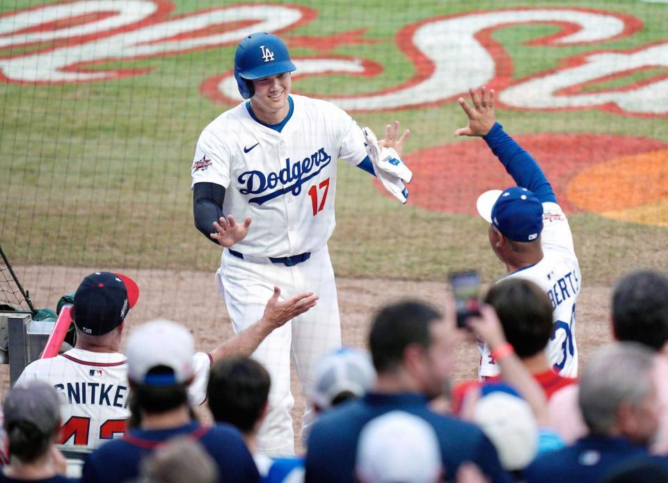 　１回、先制のホームを踏み、ベンチでロバーツ監督（右）らに迎えられるドジャース・大谷（共同）