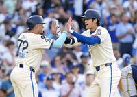 　ブルワーズ戦の３回、33ページ号２ランを放ちロハス（左）に迎えられる大谷（共同）