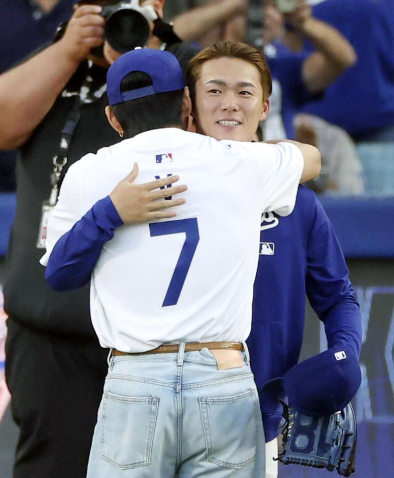 　始球式を行ったＢＴＳのＶ（手前）とハグする、捕手を務めた山本（共同）