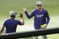 　キャッチボールを終え、タッチを交わす佐々木（右）＝共同