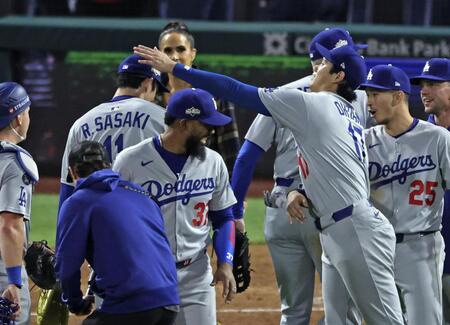 　フィリーズに勝利し、初セーブを挙げた佐々木（左奥）を迎える大谷（共同）