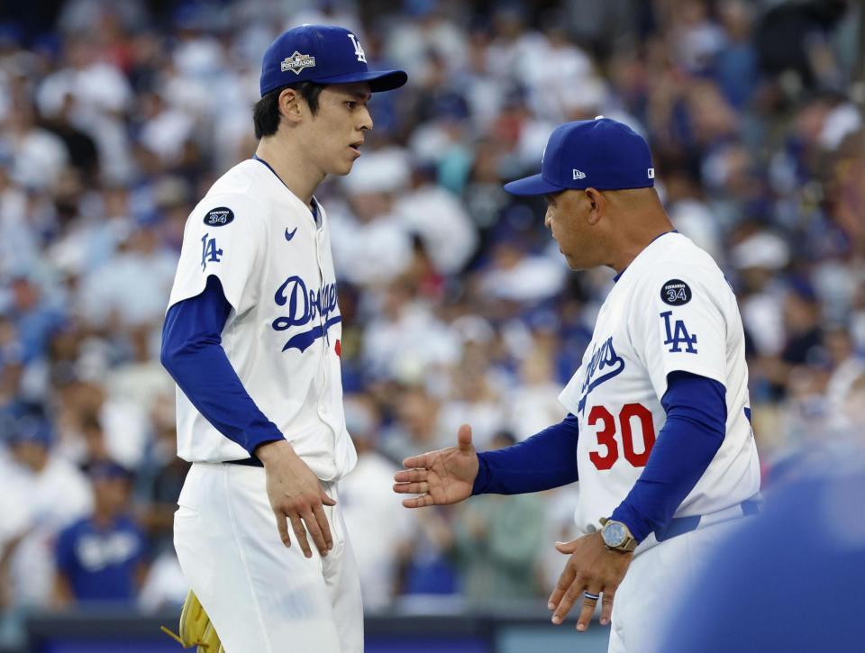 　フィリーズ戦の１０回を投げ終え、３回無安打無失点と好投した佐々木を迎えるドジャースのロバーツ監督（ゲッティ＝共同）