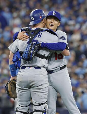 　米大リーグ、ブルージェイズとのワールドシリーズ第２戦で完投勝利を挙げ、捕手スミスと抱き合うドジャースの山本由伸（共同）