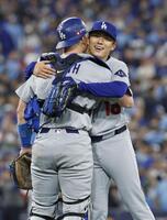 　米大リーグ、ブルージェイズとのワールドシリーズ第２戦で完投勝利を挙げ、捕手スミスと抱き合うドジャースの山本由伸（共同）