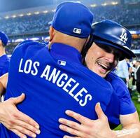 　投手用ヘルメットをかぶり、ロバーツ監督と抱き合うキケ・ヘルナンデス（ロサンゼルス・ドジャース提供）