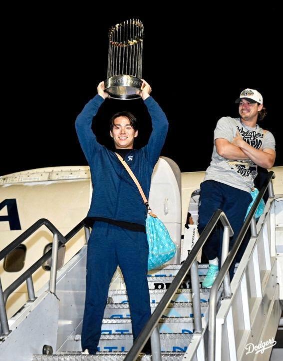 　優勝トロフィーを手に航空機から降りてくる山本（ロサンゼルス・ドジャース提供）