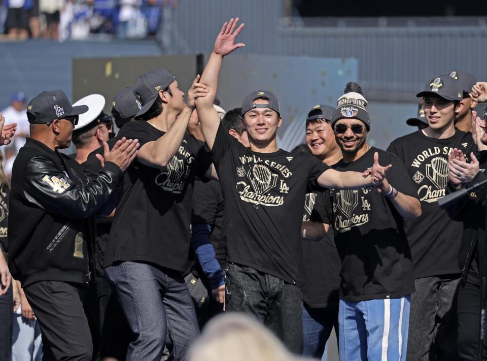 　米大リーグ、ドジャースのワールドシリーズ優勝報告会で、手を上げて歓声に応える山本由伸、その左は大谷翔平、右端は佐々木朗希（共同）