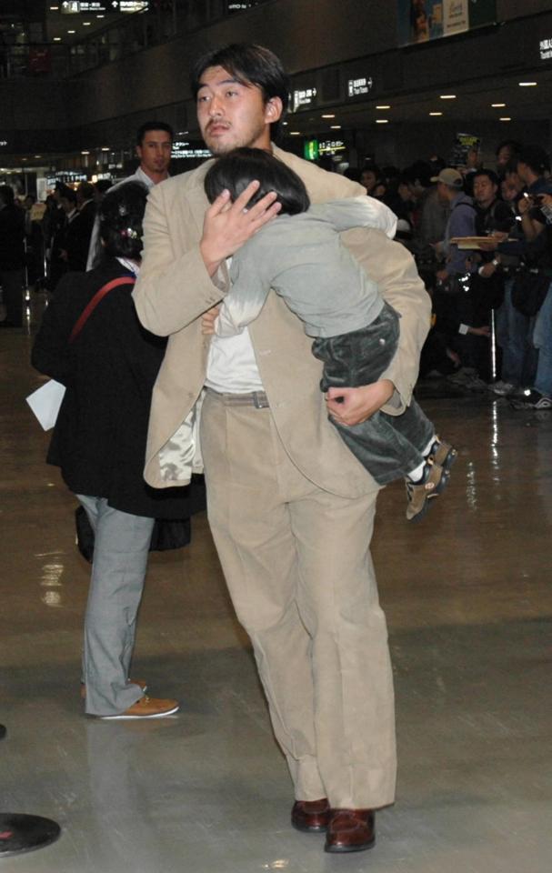 　子供を抱きかかえ帰国したドジャース・石井＝成田空港
