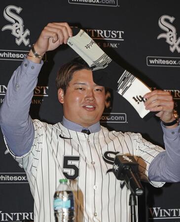 　米大リーグ、ホワイトソックスの入団記者会見で靴下を掲げる村上宗隆（共同）