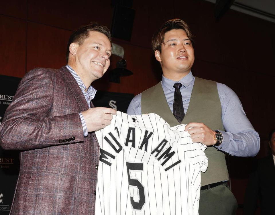 　ホワイトソックスの入団記者会見でユニホームを手にする村上宗隆。左はゲッツ・ゼネラルマネジャー（共同）