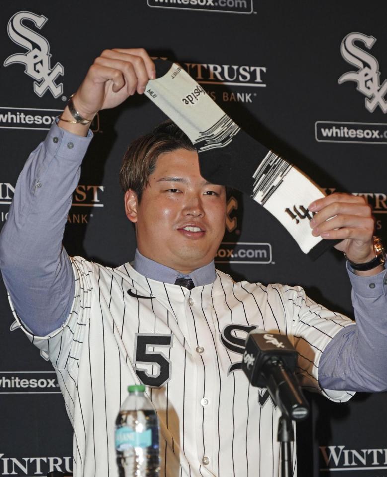 　米大リーグ、ホワイトソックスの入団記者会見で靴下を掲げる村上宗隆（共同）