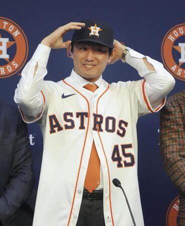 　米大リーグ、アストロズの入団記者会見で背番号「45」のユニホームに袖を通し、撮影に応じる今井達也投手（共同）