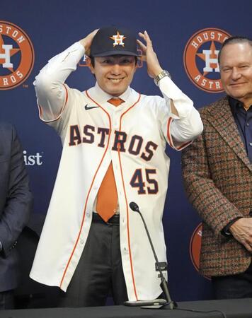 　米大リーグ、アストロズの入団記者会見で背番号「45」のユニホームに袖を通し、笑顔を見せる今井達也投手（共同）