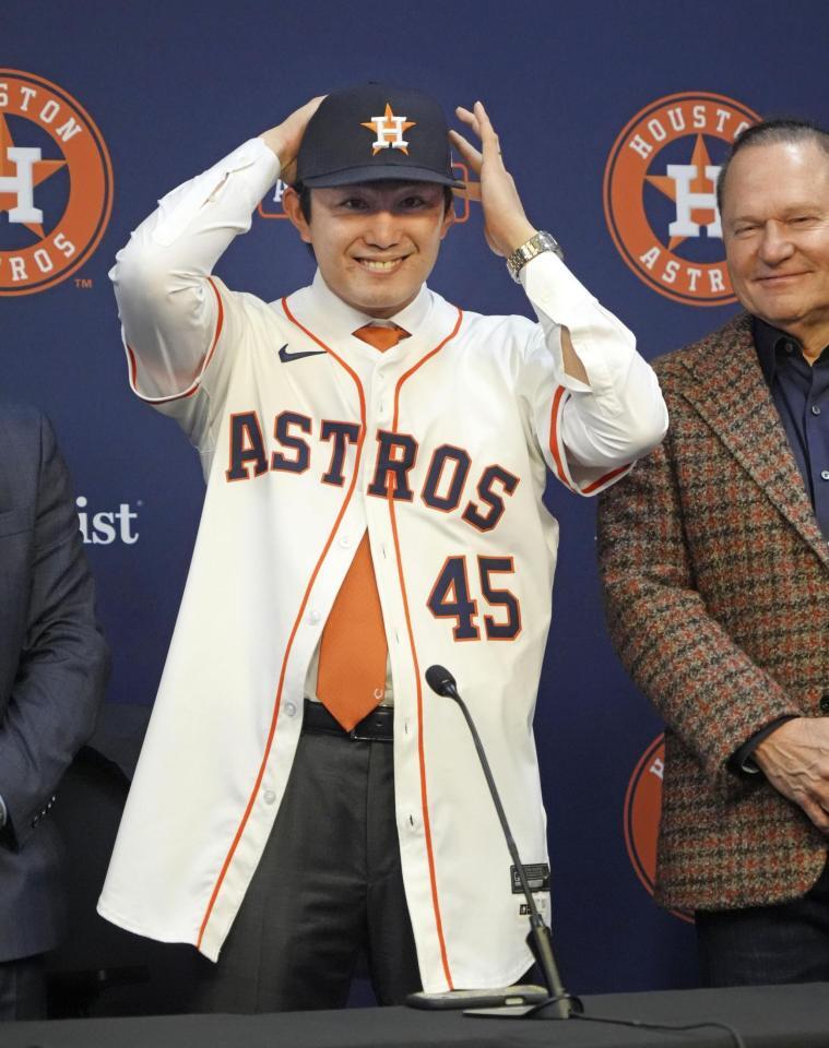 　米大リーグ、アストロズの入団記者会見で背番号「45」のユニホームに袖を通し、笑顔を見せる今井達也投手（共同）
