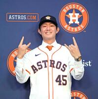　アストロズの入団会見でユニホームに袖を通し、ポーズをとる今井（共同）