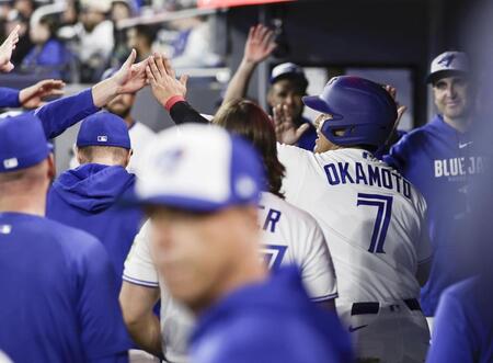 アスレチックス戦の７回、メジャー初安打を放ち、後続のゴロでアウトになった後、ベンチに戻り迎えられる岡本（７）＝トロント（共同）