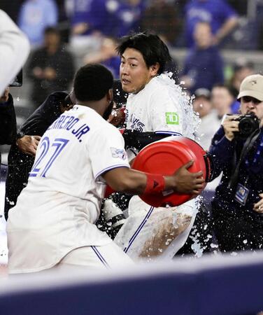 　サヨナラのホームを踏み、試合後にゲレロ（左）から手荒い祝福を受ける岡本（共同）