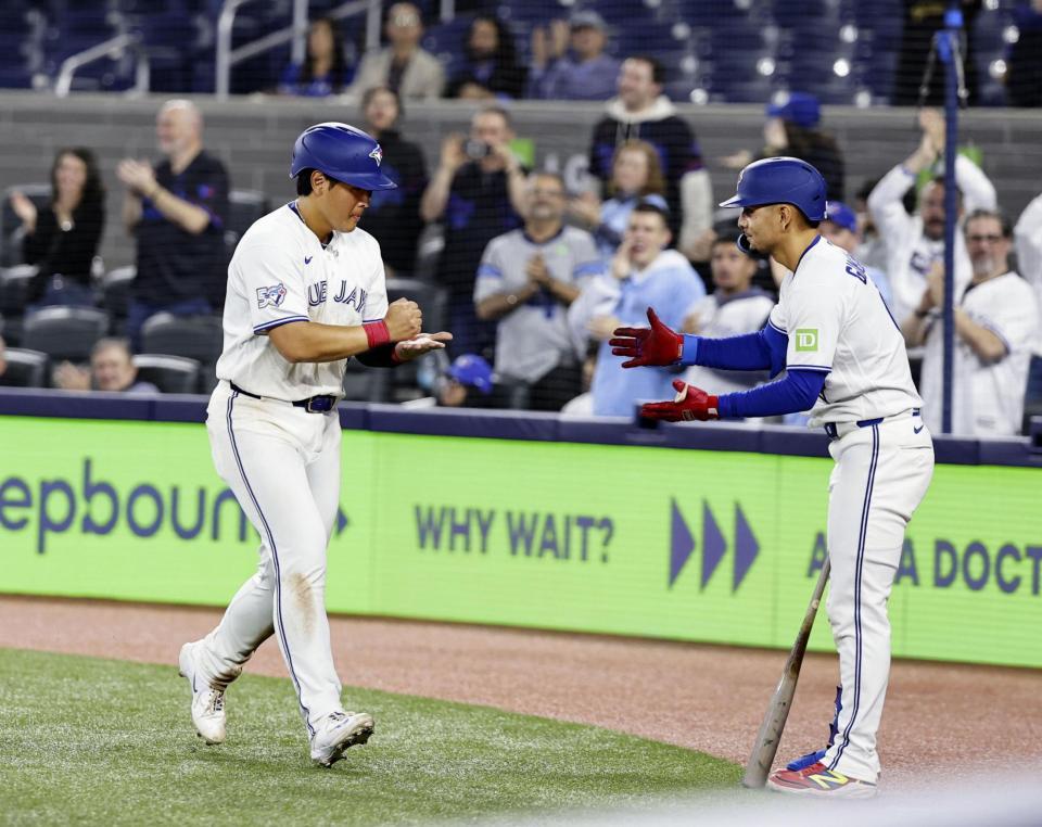 ９回、２号ソロを放ち迎えられる岡本（左）＝共同