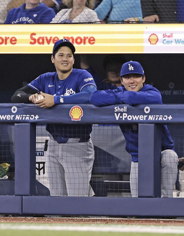 ９回、ベンチで笑顔を見せるドジャースの大谷（左）と山本（共同）