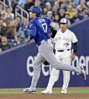 　塁を回る大谷。奥は岡本