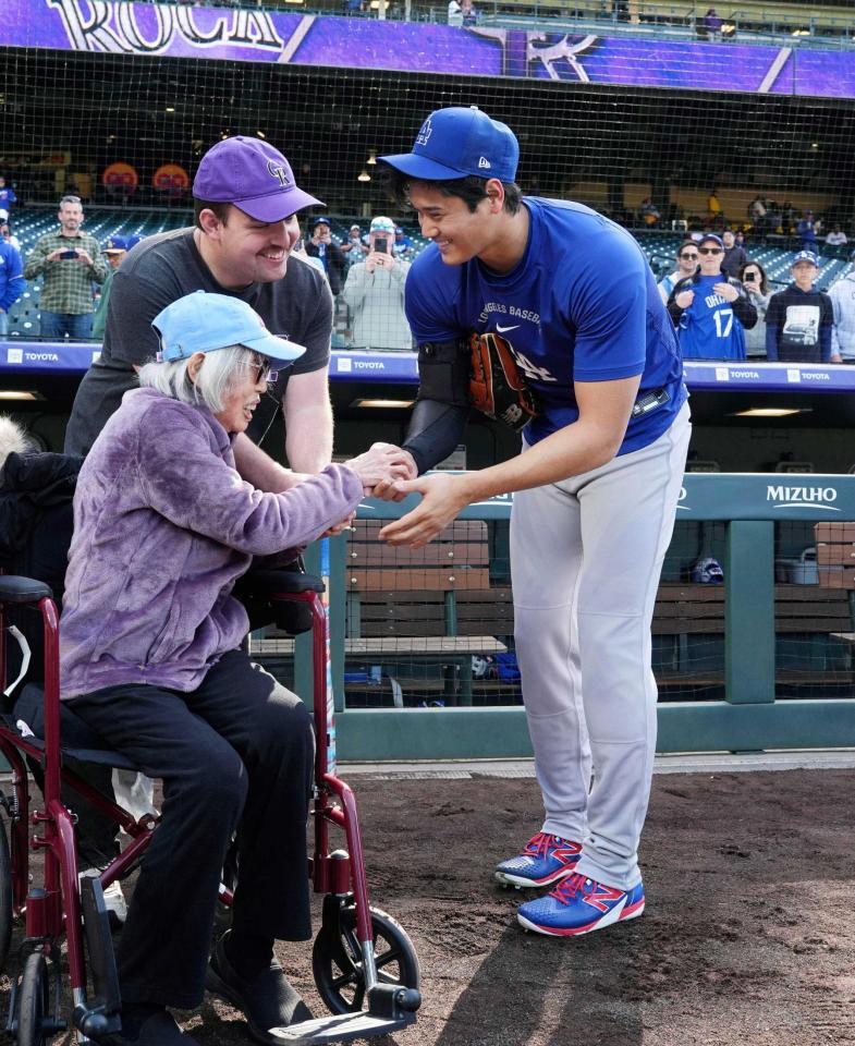 　試合前に在米被爆者のモモヨ・ナカモト・ケリーさん（左）にサインボールを手渡し、握手する大谷（共同）