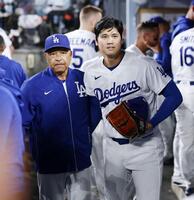 　ジャイアンツ戦の７回を投げ終えベンチに戻ったドジャース・大谷。左はロバーツ監督＝ロサンゼルス（共同）