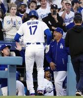 　ロッキーズ戦の１回、先頭打者本塁打を放った大谷（17）を迎えるドジャースのロバーツ監督（右隣）＝ロサンゼルス（共同）