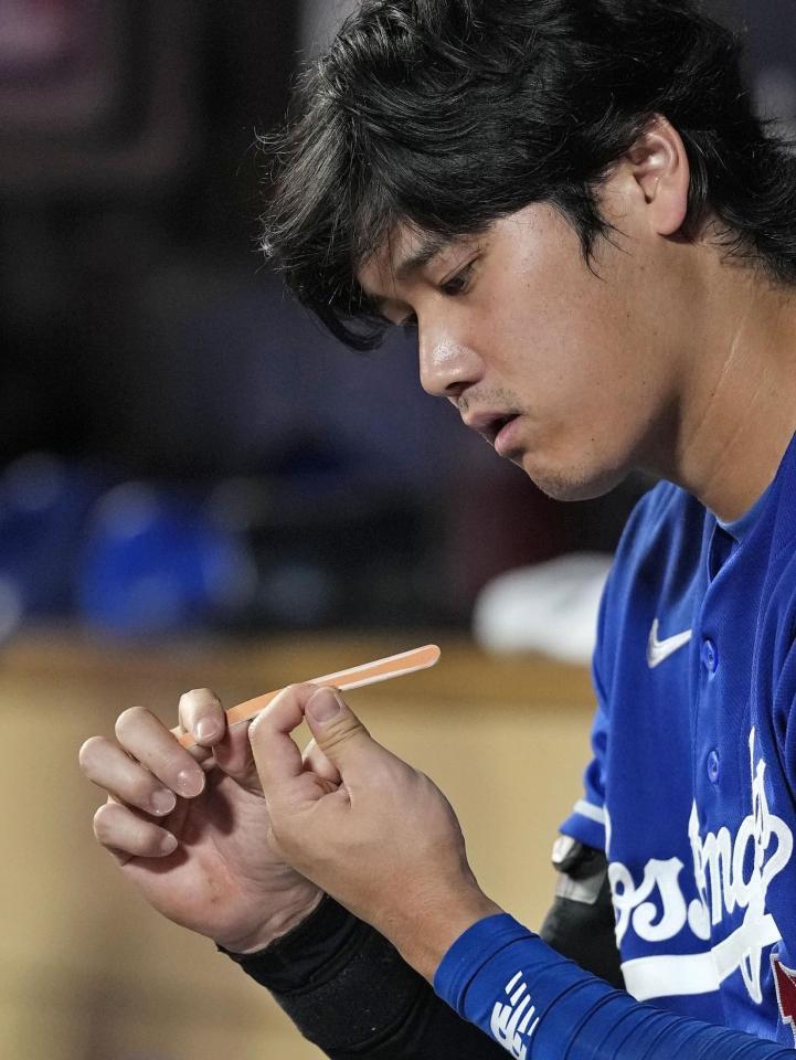　ツインズ戦のベンチで爪を整えるドジャース・大谷＝ミネアポリス（共同）