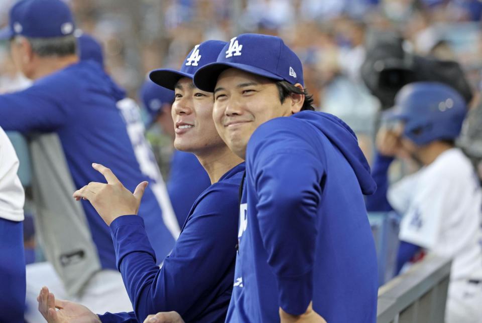 １回、ベンチで試合を見る大谷（手前）と山本（共同）