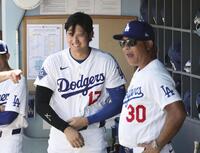 試合前、ベンチで笑顔を見せる大谷とロバーツ監督（右）＝共同