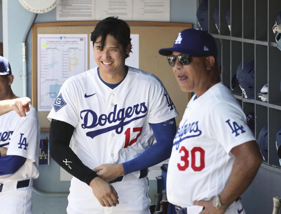 試合前、ベンチで笑顔を見せる大谷とロバーツ監督（右）＝共同
