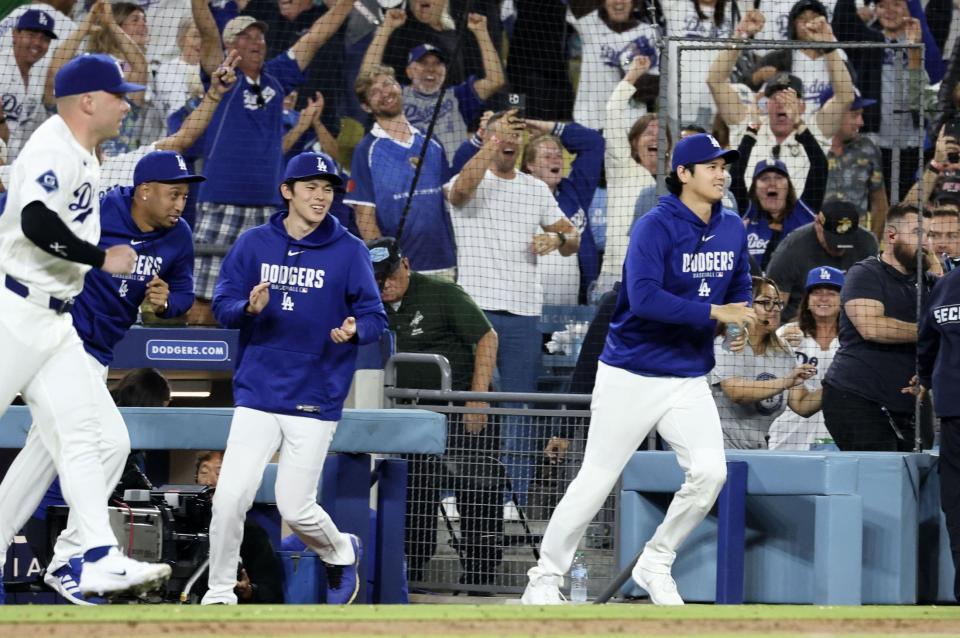 ９回、チームがサヨナラ勝ちし、ベンチから駆け出すの（右から）大谷、佐々木ら（共同）