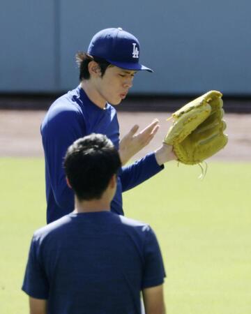 　キャッチボール中、指先を気にするドジャース・佐々木朗＝ロサンゼルス（共同）