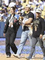 ドジャースタジアムで行われた優勝報告会を終え、デコピンを抱いて引き揚げる大谷翔平。左は妻の真美子さん（提供・共同通信社）