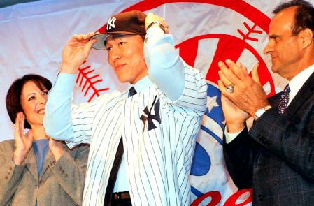 　２００３年１月、ヤンキースへの入団会見で、ユニホームを着て帽子をかぶる松井秀喜外野手。右はトーリ監督＝ニューヨーク市内のホテル（共同）