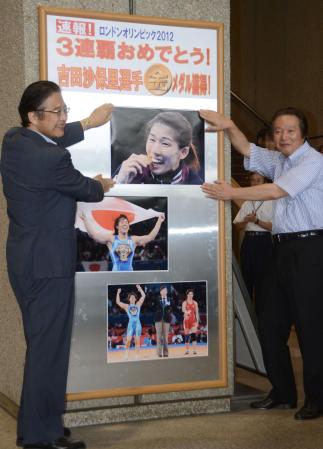 　津市役所のロビーに、吉田沙保里の優勝を伝える写真を掲示する前葉泰幸市長（左）