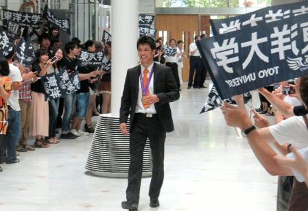 学生や職員に迎えられ、金メダルを胸にさっそうと初出勤する村田諒太