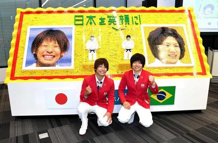 　ブロックで描かれた似顔絵の前でガッツポーズする近藤亜美（左）と中村美里