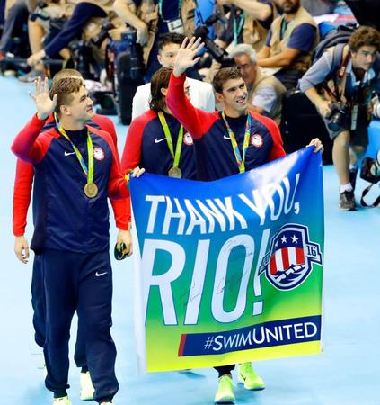　男子４００メートルメドレーリレーの表彰式を終え「ありがとう、リオ！」と書かれた垂れ幕を手に場内を歩く米国のマイケル・フェルプス（右）＝共同