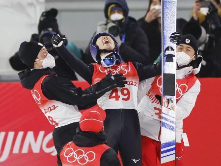 　スキージャンプの男子個人ノーマルヒルで日本選手団第１号となる金メダルを獲得し、喜ぶ小林陵侑（中央）。左は兄潤志郎＝張家口（共同）