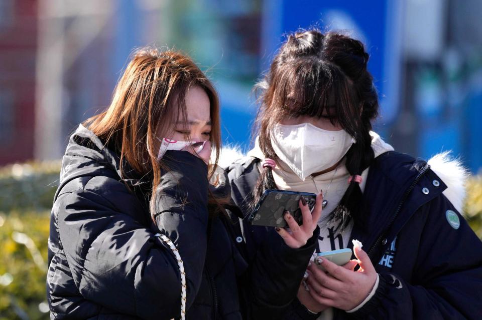 　会場の外でスマホで生中継を見ながら感極まる羽生ファン（共同）