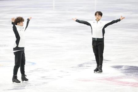 練習後、両手を広げあいさつしる鍵山優真（右）と佐藤駿＝ミラノアイススケートアリーナ（撮影・吉澤敬太