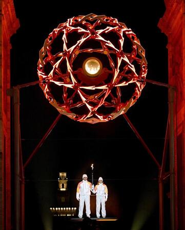 　「平和の門」でともされた聖火。左はアルベルト・トンバさん＝ミラノ（代表撮影）