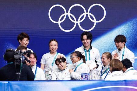 団体男子ＳＰの演技を終え、キスアンドクライで坂本花織（中央右）に頭をなでられる鍵山優真（共同）