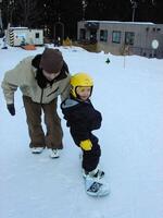 父・浩二さんに背中を押されながらスノーボードに乗る三木（家族提供）