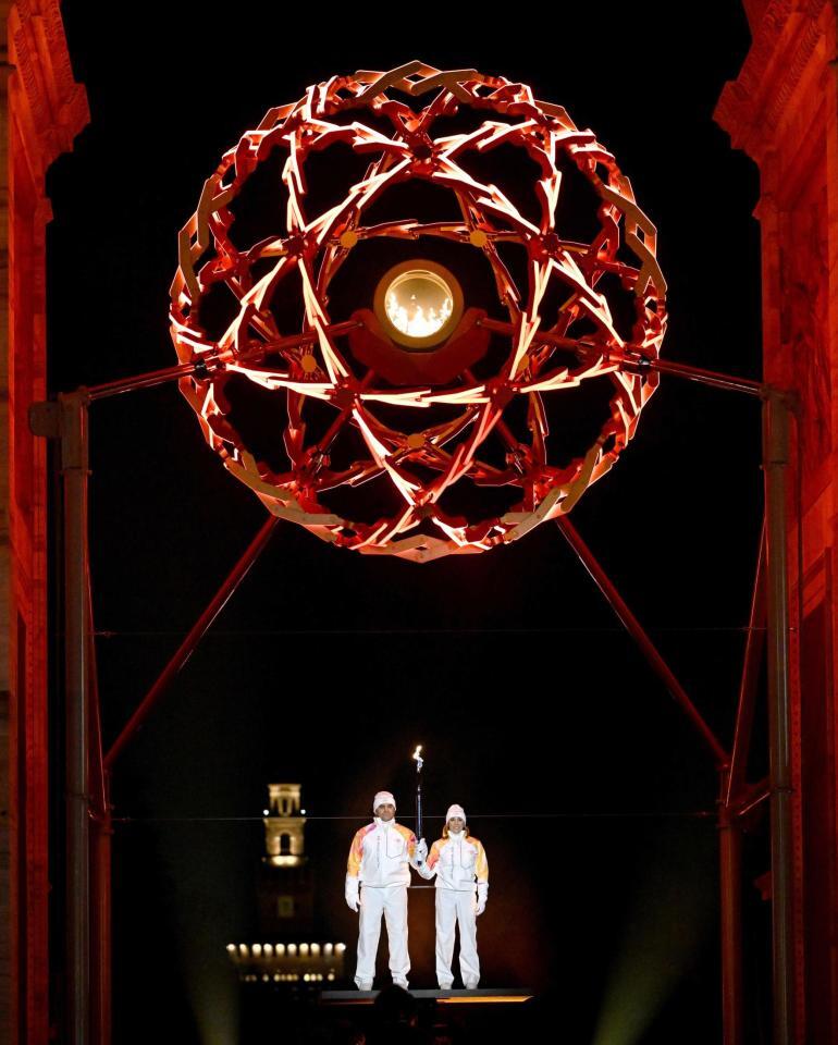 　「平和の門」でともされた聖火。左はアルベルト・トンバさん＝ミラノ（代表撮影）