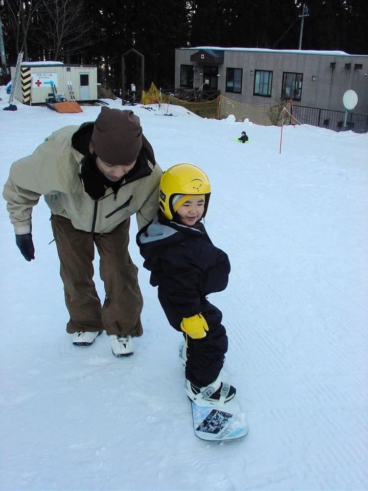 父・浩二さんに背中を押されながらスノーボードに乗る三木（家族提供）