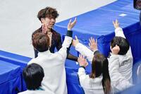 団体男子フリーの演技を終え、チームメートに迎えられる佐藤駿（奥）＝ミラノ（共同）